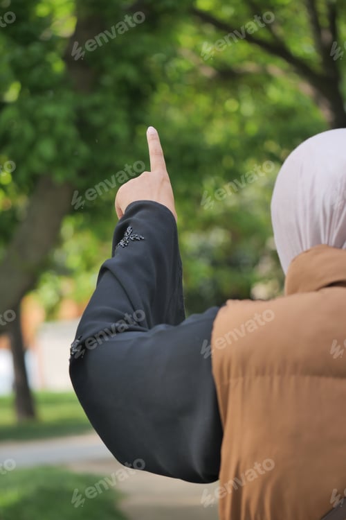 Preview: Woman pointing at a tree in a park during the day