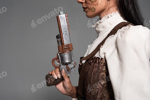 Preview: cropped view of steampunk woman holding vintage pistol isolated on grey