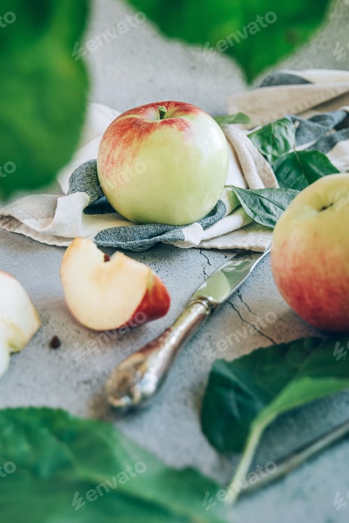 Preview: Freshly harvested ripe green red organic apples over napkin or towel and knife on table.