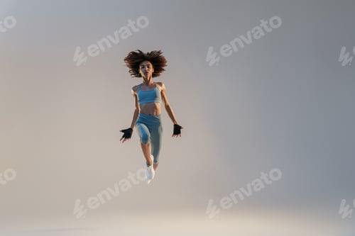 Preview: Active sporty woman in sportswear jumping on studio background. Sport and healthy lifestyle