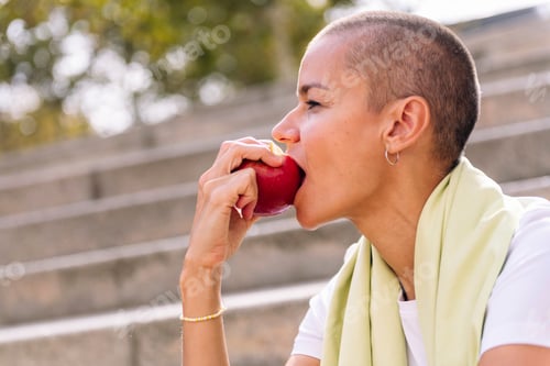 Preview: sports woman rests eating an apple after workout