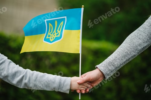 Preview: Mom and child holding flag in their hands on rally. Ukrainian yellow and blue flag flutters in wind