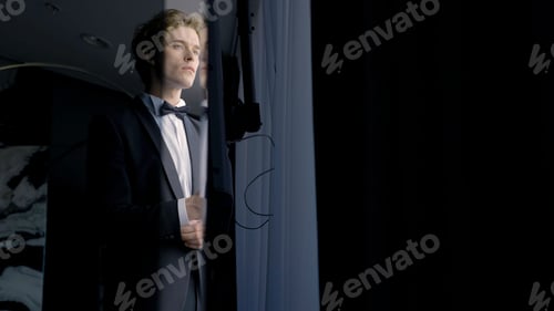 Preview: A worried groom man standing by the window. Action. Thoughtful attractive husband wearing suit
