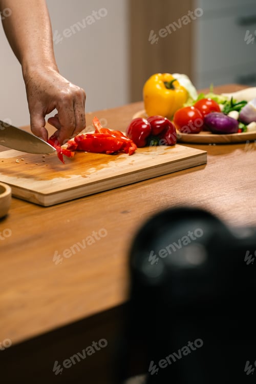 Preview: Asian man's hands cutting bell peppers in the kitchen