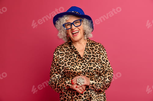Preview: Happy old age. Fashionable woman pensioner dressed in stylish leopard shirt and hat, smiles joyfully