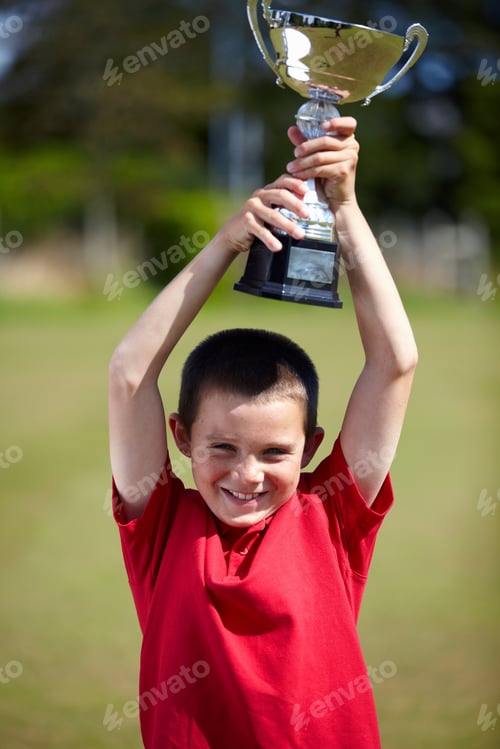 Preview: Boy cheering with trophy outdoors