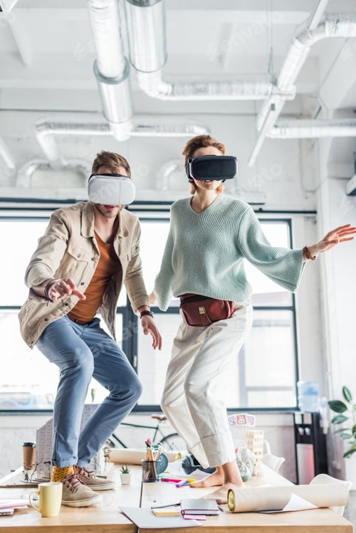Preview: female and male designers gesturing with hands while having virtual reality experience in loft