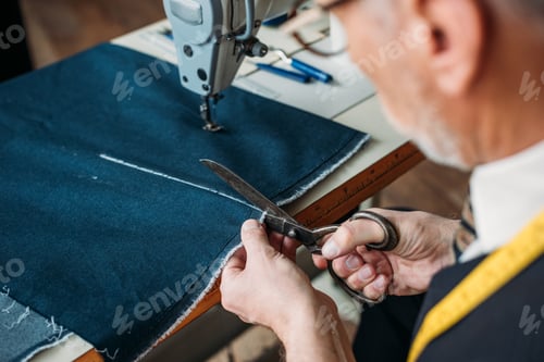 Preview: cropped image of senior tailor cutting cloth at sewing workshop