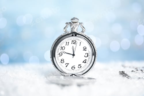 Preview: Pocket watch on snow against blurred lights. New Year countdown