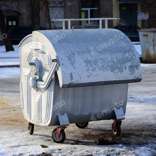 Vista previa: A silver garbage container stands near residential buildings in winter