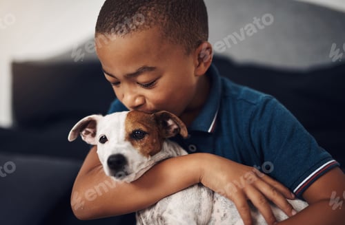 Preview: Shot of an adorable little boy playing with his pet dog on the bed at home