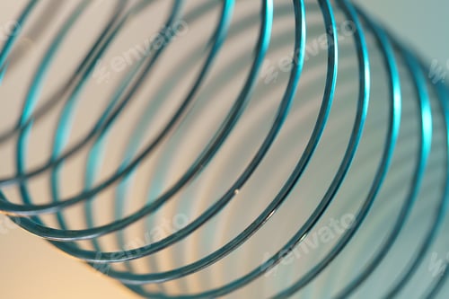 Preview: Closeup of coiled metal spring with sufficiently high strength and elastic properties in neon light