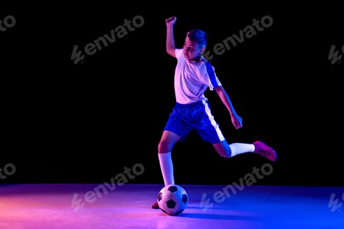 Preview: Young boy as a soccer or football player on dark studio background