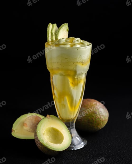 Preview: Glass of creamy, green avocado milkshake with honey, topped with fresh fruit.