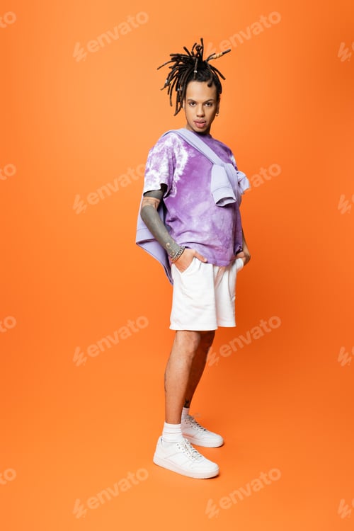 Preview: full length of multiracial man in stylish t-shirt posing with hands in pockets of white shorts on
