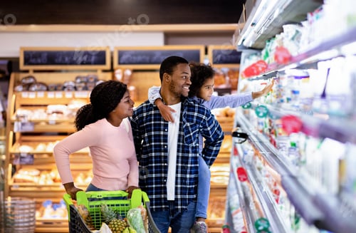Preview: Portrait of happy black family with trolley shopping together at grocery store