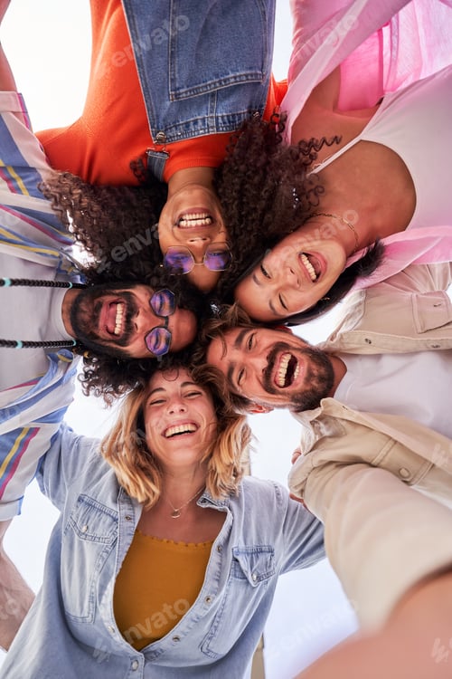 Preview: Multiethnic group of friends looking at camera cheerfully embracing each other.