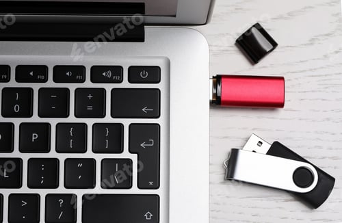 Preview: Modern usb flash drive attached into laptop on white wooden table, flat lay