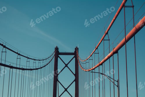 Preview: Low angle shot of the Ponte 25 de Abril bridge against a cloudless blue sky in Portugal