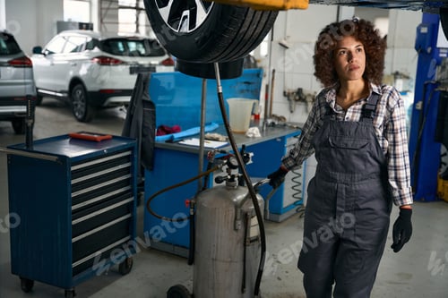 Preview: Young repairwoman in overalls pours brake fluid into special tank