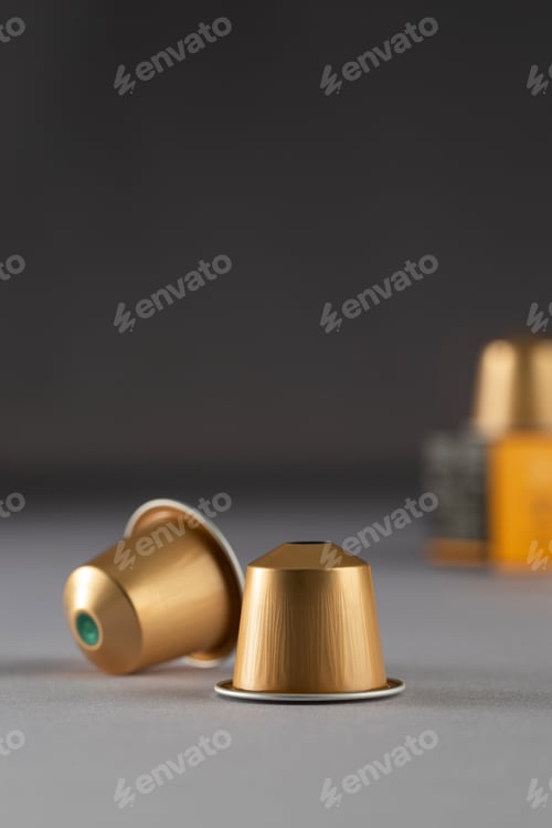 Preview: Gold coffee capsules arranged near a box on a gradient background, modern packaging