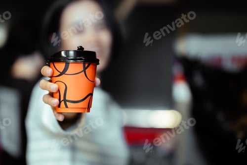Preview: hand of woman holding a take-out hot coffee at coffee shop.