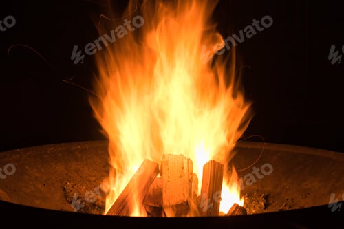 Preview: Closeup shot of a fire in black round fire pit during nighttime