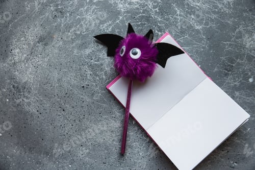 Preview: Trendy purple bat pencil and pink notebook for notes on grey background. Flat lay