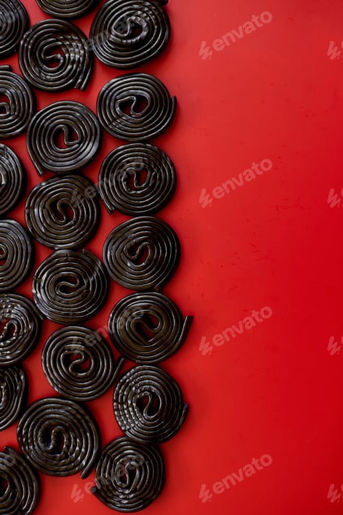 Preview: Flat lay tasty black liquorice candies on red background