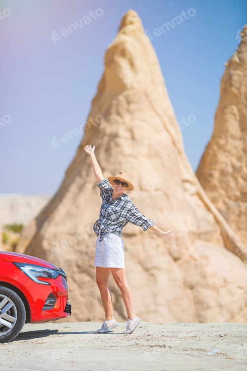Preview: Young happy woman on vacation by car in Cappadocia. Cave formations.