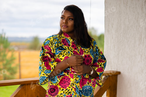 Preview: African american woman relaxing and enjoying sun while standing at terrace or balcony at sunlight at
