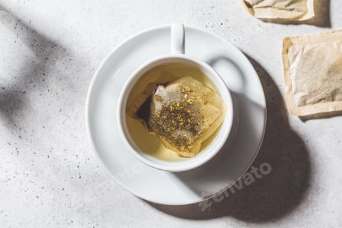 Preview: Fresh herbal tea in white cup. Herbal tea bags, top view.