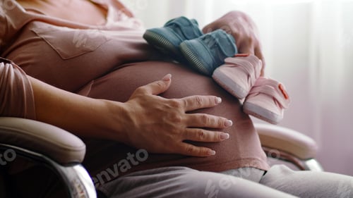 Preview: Happy pregnant woman expecting twins. Pregnant woman feeling happy at home while taking care