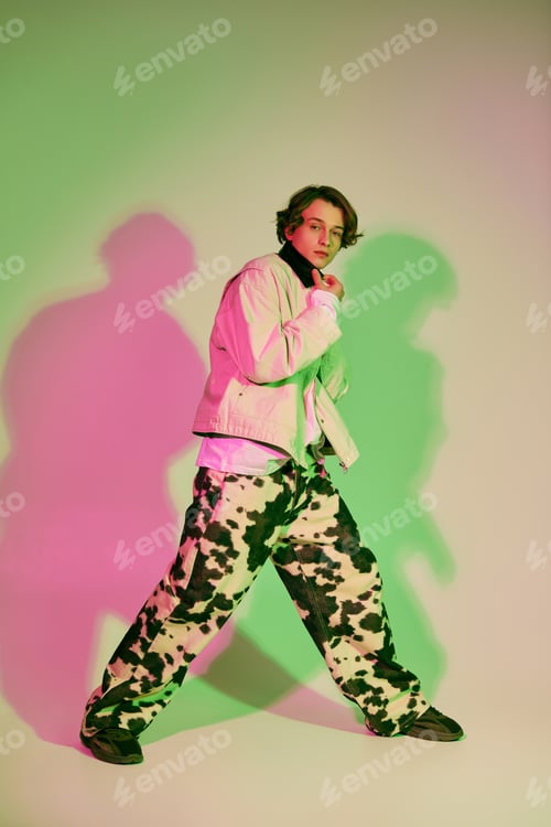 Preview: Dynamic young man in vibrant studio, showcasing contemporary fashion and unique style