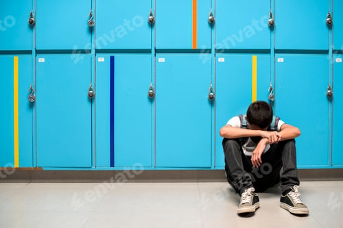 Preview: Boy sitting alone resting head on his arms