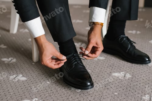 Preview: Elegant Groom Adjusting Shoes For Wedding