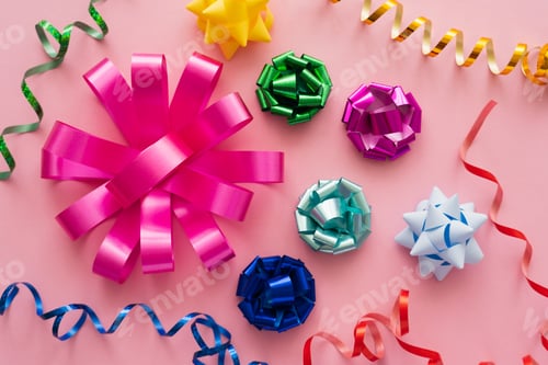 Preview: Top view of colorful gift bows and serpentine on pink background