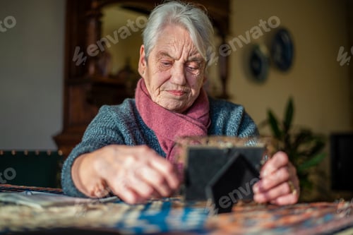 Preview: Elderly woman concentrating on a jigsaw puzzle at home