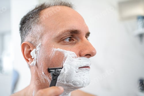 Preview: Close up portrait of man in front of shaving mirror in bathroom