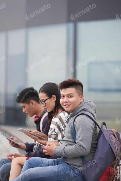 Smiling Students Using Tablets Outside Modern Building