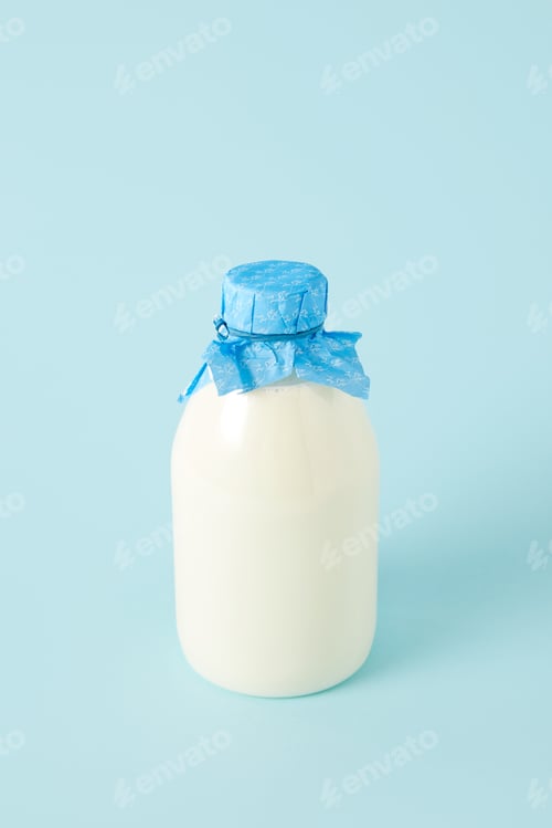 Preview: closeup shot of fresh milk in bottle wrapped by paper on blue background