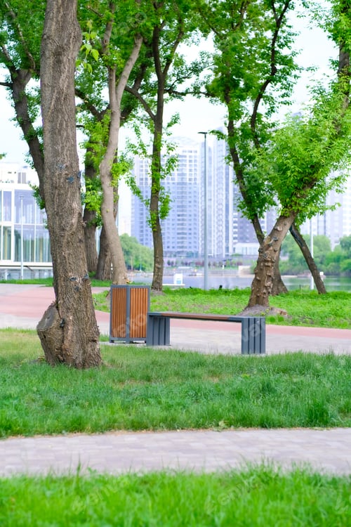 Preview: Empty bench in the park near the river. City view. Summer landscape. Recreational area. Relaxation.
