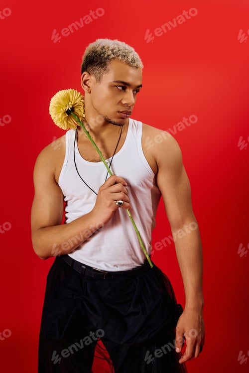 Preview: Young man embraces style with dyed hair and vibrant flower in red studio