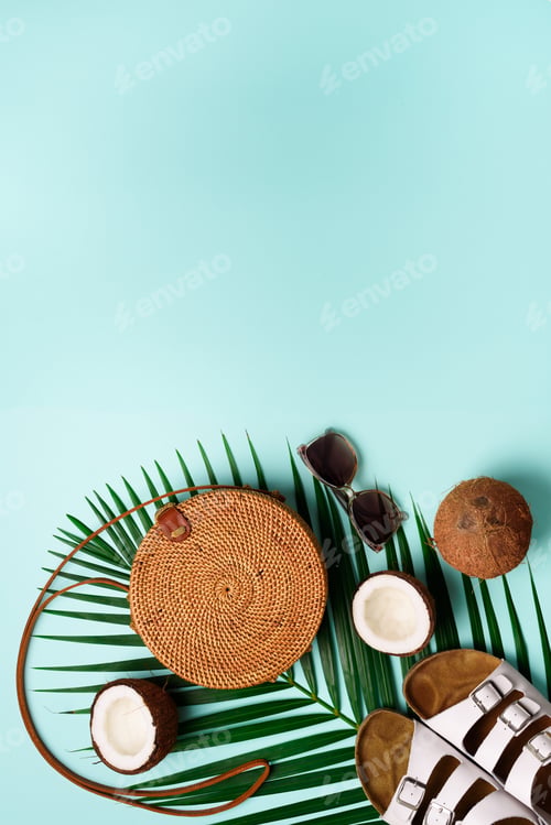 Preview: Round rattan bag, coconut, birkenstocks, palm branches, sunglasses on blue background. Banner. Top