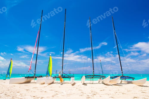 Preview: Group of catamarans with colorful sails on exotic Caribbean beach