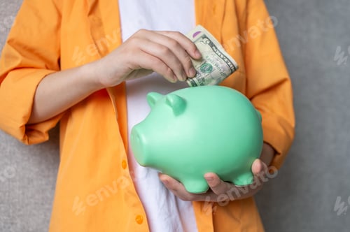 Preview: Piggy bank in the hands of a child. Put a banknote in a piggy bank