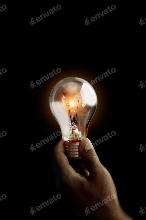 Preview: Light bulb glowing hold in hand on black background. Concept of