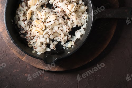 Preview: Fried onions, garlic and mustard seeds in a cast-iron frying pan. Indian food