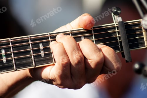 Preview: Closeup shot of a male hand playing guitar on blurred background