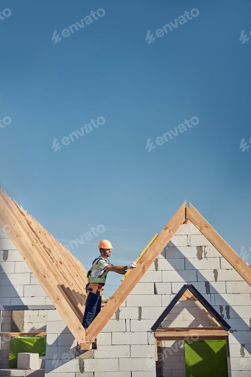 Preview: Experienced builder working on rooftop with a spirit level